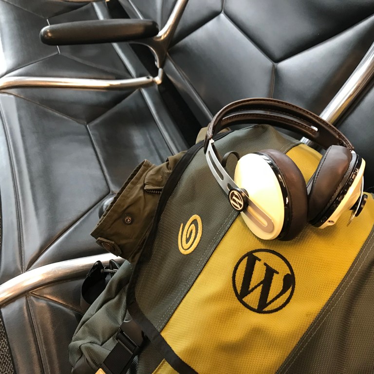 WordPress logos on backpack and headphones in airport